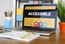 Image of a laptop on a desk. The laptop screen has the word Accessible displayed. Also in the photo is a notebook, a pencil on top of the notebook and a pencil holder is on the desk.
